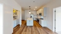 This single-floor unit at 301 N La Fox St in South Elgin, Illinois, offers a thoughtfully designed layout with modern finishes throughout. The kitchen serves as a central hub, featuring white shaker-style cabinetry with black hardware, a subway tile backsplash, light stone countertops, a central island with pendant lighting, and a full suite of stainless steel appliances including a refrigerator, range, microwave, and dishwasher. Warm-toned hardwood-style flooring runs through the kitchen and connects to an in-unit laundry area conveniently located nearby.

The bedrooms are finished with plush neutral carpeting and crisp white walls. One bedroom offers generous closet space with double doors, while another features large windows framing serene water and tree views, filling the room with natural light. A third carpeted room also benefits from natural light and direct access to a bathroom.

Two full bathrooms serve the unit, each finished with wood-look flooring, white vanities with undermount sinks, large mirrors, and bright lighting. One bathroom includes a tiled tub-shower combination with a handheld showerhead, while the other features a walk-in style shower. The overall ambiance is clean, bright, and contemporary, offering a comfortable living environment.
