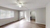 This single-floor residence offers a practical and well-organized layout designed for comfortable everyday living. The main living area is open and airy, featuring light gray walls, neutral vinyl plank flooring, a ceiling fan with integrated lighting, and a textured ceiling. Natural light filters in through blinded windows, and baseboard heaters are present throughout, ensuring year-round comfort. The living space flows openly into an adjacent dining or secondary sitting area, creating a connected and versatile floor plan.

The kitchen is compact and efficiently arranged, equipped with dark gray cabinetry, a double stainless steel sink, laminate countertops, a full-size refrigerator, and a range — providing all essential appliances in a neatly organized space.

The bedrooms are well-proportioned, each featuring vinyl plank flooring, ceiling fans, baseboard heating, and windows with blinds that allow ample natural light. One room includes a wall-mounted air conditioning unit for added climate control, while another features a built-in closet with bifold doors for convenient storage.

The bathroom is clean and modern, showcasing marble-style tile surrounding the tub and shower combo, a white vanity with a large mirror, and wood-look flooring that ties the space together cohesively. The overall aesthetic is clean, neutral, and move-in ready.