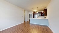 This efficiently designed 630-square-foot, one-bedroom, one-bathroom apartment is located on the ground floor at 2380 W Applebrook Lane, Unit 8-103, in Oak Creek, WI. The open-concept kitchen and living area serves as the heart of the unit, featuring rich hardwood-style flooring, a large kitchen island with a white countertop and undermount sink, dark espresso cabinetry, and a full suite of stainless steel appliances including a refrigerator, range, microwave, and dishwasher. Pendant lighting above the island adds a modern touch. The living area receives natural light through large windows flanked by blinds, with a transom window above the front entry door enhancing brightness. The 160-square-foot bedroom offers plush carpeting, a dedicated window, and direct access to a spacious walk-in closet equipped with multi-tier wire shelving for ample storage. The full bathroom features hardwood-style flooring, a dark wood vanity with white countertop, a large mirror with overhead lighting, and a shower/tub combo. Additional spaces include a utility room and dedicated closet. Neutral wall tones and clean finishes give the unit a move-in-ready appeal throughout.