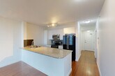 Located at 10803 Jasper Ave NW in the heart of Edmonton, AB, this well-appointed 2-bedroom, 2-bathroom unit offers a thoughtfully designed single-floor layout. Rich hardwood flooring flows consistently throughout every room, creating a warm and cohesive aesthetic.

The open-concept living area seamlessly integrates the kitchen, dining, and living spaces. The kitchen is a standout feature, equipped with white cabinetry, stainless steel appliances including a built-in microwave, electric range, and a large refrigerator. A granite-topped peninsula with a double stainless steel sink serves as both a functional workspace and a natural divider between the kitchen and living areas. A mosaic tile backsplash adds a modern decorative touch.

A bright hallway connects the main living area to the two bedrooms, each offering clean white walls and hardwood flooring. The primary bedroom provides a comfortable and private retreat, while the second bedroom offers flexible use. Three closets throughout the unit ensure ample storage.

Both bathrooms continue the granite countertop theme, featuring white vanities and framed mirrors. One bathroom includes a shower-tub combination, while the other is fitted with a standalone shower. In-unit laundry adds everyday convenience to this efficiently designed urban home.