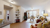 This single-floor residence offers a thoughtfully designed layout that balances comfort and functionality throughout. An entry hallway, accented by decorative wall art and a framed mirror, leads into the main living areas, creating a warm first impression.

The living room is a generously sized gathering space featuring warm wood-look flooring, a ceiling fan, and a large window that invites abundant natural light and outdoor views. Built-in corner shelving provides both display space and architectural interest, while the room's open feel makes it ideal for relaxed everyday living.

Adjacent to the living room, the open-concept dining and kitchen area is centered around a raised dining table beneath a pendant light fixture. The kitchen is equipped with light wood cabinetry, granite-style countertops, a double sink, and black appliances including a range and refrigerator, with a peninsula counter that connects the spaces seamlessly.

The primary bedroom is a tranquil retreat with a ceiling fan, warm flooring, and a large window dressed with elegant curtains. A second bedroom offers bright, cheerful character with generous window light. The bathroom features a light wood vanity with granite-style countertops, overhead lighting, and a large mirror. Completing the home is a dedicated in-unit laundry area with side-by-side washer and dryer and overhead shelving for added storage convenience.