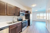 Located at S 34th St & Broadway in Council Bluffs, Iowa, this single-floor unit offers a well-designed layout that maximizes every square foot. The open-concept living area seamlessly integrates the kitchen, dining, and living spaces, creating a cohesive and functional environment. Light-toned hardwood-style flooring runs throughout, lending a clean and modern aesthetic that brightens the interior.

The kitchen is a standout feature, outfitted with rich dark-stained wood cabinetry extending to the upper walls for ample storage, crisp white countertops, a classic subway tile backsplash, and a full suite of stainless steel appliances including a refrigerator, electric range, over-the-range microwave, and dishwasher. A double-basin stainless steel sink completes the workspace.

The living area benefits from a large window that draws in natural light and offers outdoor views, complemented by a ceiling fan for added comfort. The bathroom is clean and functional, featuring a matching dark wood vanity, a white countertop with an integrated sink, and a full tub-shower combination. Two closets provide generous storage, and a dedicated laundry area adds everyday convenience. The unit's cohesive design and practical layout make it a well-appointed living space.