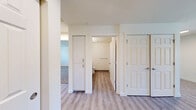 Located at 4800 B St in Springfield, Oregon, this well-appointed two-bedroom, two-bathroom residence offers a comfortable and functional layout across a single floor. The kitchen is a standout feature, equipped with white shaker-style cabinetry, granite-look countertops, and black appliances including a refrigerator, electric range with overhead ventilation, and dishwasher. Light wood-look vinyl plank flooring runs throughout the main living areas, creating a clean and cohesive aesthetic. The combined kitchen and living area provides a practical, open feel with natural light filtering in through blinds-covered windows. Both bedrooms are carpeted for added comfort; the spacious primary bedroom offers generous square footage, while the second bedroom is well-sized with a sliding closet and a wall-mounted HVAC unit. The two bathrooms offer distinct configurations — one includes a full soaking tub with a shower and grab bar, while the other features a walk-in shower stall with a vanity and cabinet storage. A private balcony off the main living area overlooks a well-maintained community courtyard with landscaping and neighboring buildings. The unit's neutral color palette and modern fixtures provide a move-in-ready environment throughout.