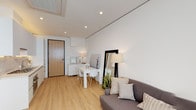 Located at 115 S Fairfax Ave in Los Angeles, this single-floor unit presents a clean, modern aesthetic defined by a neutral palette, light wood flooring, and recessed lighting throughout. The open-plan living and dining area provides a functional yet stylish layout, with ample space for a seating area and a dining table. Large windows fitted with roller shades allow natural light to filter in, contributing to the bright and airy atmosphere.

The kitchen is sleekly designed with white flat-front cabinetry, a marble-style backsplash, stone countertops, and stainless steel appliances including a gas cooktop and built-in oven. The efficient layout maximizes utility within a compact footprint.

The bedroom is thoughtfully outfitted with floor-to-ceiling built-in cabinetry in matte gray, incorporating open shelving at headboard height for both storage and display. A window provides natural light and connects the room to the outside.

The bathroom features large-format tile flooring, a glass-enclosed walk-in shower with stone-tiled walls, and a clean, contemporary finish. The overall design of the space prioritizes smart use of space and a cohesive modern sensibility throughout.