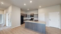 This thoughtfully laid-out single-floor residence offers three bedrooms and three bathrooms within a comfortable and functional floor plan. The open-concept kitchen and living area serves as the heart of the home, featuring a central island with a granite countertop and integrated sink, dark espresso cabinetry with open shelving, and a full suite of black appliances including a refrigerator, range, microwave, and dishwasher. Light wood-look flooring flows throughout the main living spaces, creating a warm and cohesive aesthetic complemented by recessed lighting and neutral wall tones.

The living area is bright and open, with a sliding glass door fitted with vertical blinds that leads to a private balcony, allowing natural light to fill the space. Each bedroom offers a comfortable footprint, with plush carpeting, ceiling fans, and windows dressed with horizontal blinds. The primary bedroom is generously sized and well-proportioned. The bathrooms continue the home's consistent design language, showcasing granite-topped dark vanities, framed mirrors, and wood-look tile flooring. Throughout, the clean lines, neutral palette, and modern finishes combine to create a polished and move-in-ready living environment.