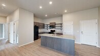 This thoughtfully laid-out single-floor residence offers three bedrooms and three bathrooms within a comfortable and functional floor plan. The open-concept kitchen and living area serves as the heart of the home, featuring a central island with a granite countertop and integrated sink, dark espresso cabinetry with open shelving, and a full suite of black appliances including a refrigerator, range, microwave, and dishwasher. Light wood-look flooring flows throughout the main living spaces, creating a warm and cohesive aesthetic complemented by recessed lighting and neutral wall tones.

The living area is bright and open, with a sliding glass door fitted with vertical blinds that leads to a private balcony, allowing natural light to fill the space. Each bedroom offers a comfortable footprint, with plush carpeting, ceiling fans, and windows dressed with horizontal blinds. The primary bedroom is generously sized and well-proportioned. The bathrooms continue the home's consistent design language, showcasing granite-topped dark vanities, framed mirrors, and wood-look tile flooring. Throughout, the clean lines, neutral palette, and modern finishes combine to create a polished and move-in-ready living environment.
