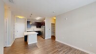 Located in the heart of downtown Indianapolis on E Market Street, this 2-bedroom, 3-bathroom residence offers a thoughtfully designed single-floor layout. The open-concept kitchen and living area serves as the centerpiece of the home, featuring rich dark-espresso cabinetry, stainless steel appliances including a refrigerator, range, microwave, and dishwasher, and a generous island with a light quartz countertop, illuminated by stylish pendant lighting. Wood-look flooring flows throughout the main living areas, adding warmth and continuity. The living space receives natural light through large windows dressed with blinds. Both bedrooms are carpeted and well-sized, with the primary bedroom offering notable square footage and multiple windows. The bathrooms are finished with dark vanity cabinetry, white quartz countertops, large mirrors, and tiled tub-shower combinations featuring an elegant mosaic accent border. Four closets, including walk-in options with wire shelving, provide abundant storage. A dedicated laundry area adds everyday convenience. The neutral color palette and clean, modern aesthetic throughout create a cohesive and functional living environment well-suited to urban life.