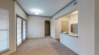 This single-story residence located on Shoreline Drive in Austin, Texas, offers a well-organized layout with a cohesive, neutral aesthetic throughout. The open-concept living and dining area is generously sized, featuring plush carpeting, crown molding, and an arched doorway that adds architectural character. Large windows fitted with blinds allow abundant natural light to fill the space, while a separate living room showcases a classic fireplace with a white mantel, built-in shelving, and a ceiling fan overhead—creating a comfortable, functional gathering area.

The kitchen is well-appointed with white shaker-style cabinetry, light quartz countertops, a grey subway tile backsplash, and stainless steel appliances including a gas range, microwave, and dishwasher. A peninsula counter connects the kitchen to the dining and living areas, enhancing the open flow of the home.

The bedrooms are carpeted and bright, each featuring windows with natural light and ceiling fans where applicable. Six-panel doors with lever hardware appear consistently throughout the unit. The bathroom offers wood-look flooring, white cabinetry with ample drawer storage, and a well-lit vanity with a large mirror. Overall, the space maintains a clean, neutral palette with warm finishes throughout.