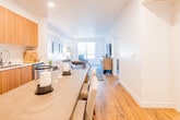 Located at 1031 Walnut Ave in Fremont, this single-floor residence presents a thoughtfully designed open-concept layout that seamlessly connects the kitchen, dining, and living areas. Warm-toned hardwood flooring runs throughout the main living spaces, creating a cohesive and inviting atmosphere.

The kitchen is a standout feature, outfitted with flat-front wood cabinetry extending to the ceiling, white subway tile backsplash, bright white countertops, and a full suite of stainless steel appliances including a gas range, over-the-range microwave, refrigerator, and dishwasher. A dining table positioned adjacent to the kitchen provides a natural transition into the open living area.

The living room receives ample natural light through a large window offering views of surrounding greenery. Architectural details such as ceiling beams add visual interest to the space.

The bedroom is carpeted for comfort and features windows with outdoor views, providing a calm and restful environment with generous wall space. A dedicated closet offers practical storage.

The bathroom includes a full tub-shower combination with marble-style tile surround and chrome fixtures, complemented by hardwood flooring and access to a walk-in closet area. Recessed lighting throughout the residence ensures consistent, well-distributed illumination across all rooms.