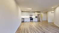 Located at 8035 Boulevard du St-Laurent in Brossard, Quebec, this well-designed one-bedroom, one-bathroom unit offers a clean, modern aesthetic throughout. The open-concept living and kitchen area is bright and airy, featuring light wood-style laminate flooring that flows seamlessly through the space. Large sliding glass doors in the living area invite natural light and provide views of the greenery outside, creating a welcoming atmosphere. A track lighting fixture and recessed pot lights ensure the space is well-lit at all times of day.

The kitchen is outfitted with high-gloss white cabinetry extending to the ceiling, a white tile backsplash, light countertops, and a full suite of stainless steel appliances including a refrigerator, electric range, built-in microwave, and dishwasher. The bedroom is a comfortable size, featuring a sliding frosted-glass closet door and recessed lighting. The bathroom is finished with large-format beige floor tiles, crisp white wall tiles surrounding the bathtub, a modern floating wood-toned vanity with a wide mirror, and a wall-mounted storage cabinet. A dedicated in-unit laundry area with a front-loading washer and shelving adds everyday convenience to this thoughtfully appointed home.
