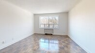 Located at 99 Dowling Avenue in Toronto's vibrant Parkdale neighbourhood, this well-appointed 2-bedroom, 1-bathroom unit offers a thoughtfully designed single-floor layout. Gleaming parquet hardwood floors run throughout the living, dining, and bedroom areas, lending warmth and character to the bright, neutral-toned interiors. The living room is generously proportioned, featuring a large window with outdoor views and a classic radiator, allowing natural light to fill the space. The dining area flows naturally from the living space, creating a seamless open feel. The galley-style kitchen is smartly updated with white shaker cabinetry, dark countertops, a subway tile backsplash, stainless steel appliances including a full-size refrigerator and stove, and recessed track lighting overhead. Both bedrooms are comfortably sized, each offering windows with outdoor views and radiator heating. The spacious primary bedroom includes mirrored sliding closet doors. The unit also features three closets in total for ample storage. The bathroom is finished with clean subway tile surrounding a full soaking tub and neutral stone-look floor tiles. A dedicated entrance and hallway complete this functional and stylish home.