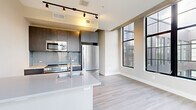 Located at 713 Lamont Street Northwest in Washington, DC, this well-appointed one-bedroom, one-bathroom residence offers a thoughtfully designed layout with modern finishes throughout. Light-toned hardwood flooring flows seamlessly across the open living area, creating a cohesive and airy feel.

The kitchen serves as a central highlight, featuring a large island with an integrated sink and sleek white countertops, dark wood cabinetry, a tiled backsplash, and a full suite of stainless steel appliances including a refrigerator, range, and built-in microwave. Track lighting overhead adds both functionality and a contemporary aesthetic. Floor-to-ceiling steel-framed windows along the living area flood the space with natural light and offer views of the surrounding neighborhood.

The bedroom is a comfortable, well-proportioned retreat with light walls, hardwood flooring, and clean white baseboards. A hallway connects the main living areas and provides access to a closet with sliding panel doors and built-in hanging storage, offering practical organization options.

The bathroom is finished in neutral tones, featuring a tub-shower combination with white tile surround, a white vanity with undermount sink, and coordinating chrome fixtures. The overall design of this residence balances modern urban style with functional, everyday livability in the heart of Washington, DC.