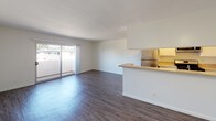 Located in the Northridge neighborhood of Los Angeles, this single-floor residence on Merridy Street offers a well-designed layout with clean, modern finishes throughout. The open-concept living and dining area is grounded by durable wood-style flooring and bright white walls, creating a light and airy atmosphere. A sliding glass door leads directly to a private balcony, allowing natural light to flow into the space while providing an outdoor retreat with neighborhood views. The kitchen is thoughtfully designed in a galley configuration, featuring granite-style countertops, white cabinetry, stainless steel appliances including a gas range with overhead microwave, and a peninsula that opens to the living area. The bedroom areas are finished with plush carpet, providing a comfortable and quiet retreat. Each bedroom offers ample wall space and access to natural light through well-placed windows. The bathroom is equipped with a tub and shower combination enclosed by a framed sliding glass door with chrome fixtures, maintaining a clean and functional aesthetic. Throughout the residence, consistent white walls, efficient ceiling ventilation, and thoughtful transitions between spaces contribute to a cohesive and comfortable living environment.