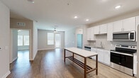 Located at 11317 Lomu Rd in Mauldin, SC, this single-story 2-bedroom, 3-bathroom home offers a thoughtfully designed open-concept layout with consistent wood-look flooring throughout. The kitchen is a standout feature, boasting white shaker cabinetry, a classic subway tile backsplash, granite countertops, stainless steel appliances including a range and microwave, and a central island that flows seamlessly into the bright living area. Recessed lighting and a ceiling fan enhance the open living and dining space, which is bathed in natural light from large windows and a glass door leading outside. The generously sized primary bedroom includes a ceiling fan, natural light from dual windows, and direct access to a well-appointed en suite bathroom featuring a vanity with white cabinetry, a glass-enclosed shower, and a walk-in closet with wire shelving. The second bedroom also features a ceiling fan and a window with outdoor views. Additional bathrooms include a tub-shower combination with white tile surround. A dedicated laundry room houses a full-size washer and dryer. Two closets and a laundry room complete this practical and modern home.