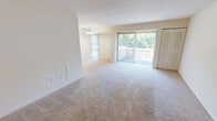 Located at 1011 Cloister Rd in Wilmington, Delaware, this two-bedroom, two-bathroom apartment offers a practical and comfortable single-floor layout. The open combined kitchen and living area serves as the heart of the home, with the kitchen featuring light wood cabinetry, dark granite-style countertops, a black refrigerator, tile flooring, and a dedicated walk-in pantry with built-in shelving for ample storage. The living room is generously sized, finished with soft wall-to-wall carpeting and neutral warm tones throughout. Sliding glass doors flood the space with natural light and open onto a private balcony overlooking lush greenery, complemented by vertical blinds and a closet with louvered doors. A chandelier adds a subtle decorative touch to the adjoining dining area. The spacious primary bedroom offers room for a full furniture arrangement, complete with carpeting, closet access, and a private en-suite bathroom. The second bedroom is also well-proportioned with carpeted floors and its own closet. Both bathrooms are clean and functional. The unit's neutral palette, abundant natural light, and thoughtful storage solutions make it a comfortable and move-in ready residence.