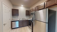Located at 2100 N Leverett Ave in Fayetteville, Arkansas, this single-floor unit offers a clean, functional layout designed for comfortable everyday living. The kitchen is well-appointed with rich, dark wood cabinetry, light granite-style countertops, and a full suite of stainless steel appliances including a refrigerator, electric range, built-in microwave, and dishwasher. Light wood-style luxury vinyl flooring runs throughout the unit, lending a bright and cohesive feel to the space.

The open living area is airy and versatile, featuring neutral gray walls, ceiling fans, and a front entry door flanked by a window fitted with blinds that allow for natural light and privacy. The layout flows efficiently between the living space and kitchen, with easy access to the bedroom and bathroom.

The bedroom is a calm, well-lit retreat with a window overlooking greenery, ceiling fan, and ample wall space. The bathroom is neatly finished in a neutral palette, offering a full tub-shower combo, granite-style vanity countertop, dark wood cabinetry, and direct access to a walk-in closet with shelving. Throughout the unit, clean lines, consistent finishes, and practical design elements create a comfortable and move-in-ready living environment.