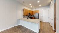 Located at 1001 W Rosedale St in Fort Worth, TX, this well-designed one-bedroom, one-bathroom residence offers a smart and efficient layout across a single floor. The open-concept living area seamlessly integrates the kitchen, dining, and living spaces, creating a bright and cohesive environment. The kitchen is a standout feature, showcasing warm wood cabinetry, a textured stone tile backsplash, granite-look countertops, and a peninsula island with pendant lighting overhead. Stainless steel appliances — including a refrigerator, electric range, over-the-range microwave, and dishwasher — complete the modern culinary setup. Wood-look plank flooring runs throughout the unit, lending warmth and continuity to each room. The bedroom offers a comfortable footprint with natural light streaming through double windows dressed with blinds. The bathroom features a full soaking tub with tiled shower surround, a granite-topped vanity, and direct access to a spacious walk-in closet with multi-level shelving and hanging rods. Additional conveniences include a dedicated laundry area and a hallway connecting the living spaces to the private quarters, ensuring a practical and well-organized flow throughout the home.