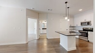 Located at 1500 Bell Road in Nashville, TN, this well-appointed one-bedroom, one-bathroom unit offers a thoughtfully designed open-concept layout across a single floor. The kitchen serves as a central highlight, featuring crisp white shaker cabinets with matte black hardware, dark countertops, a kitchen island with pendant lighting, and a full suite of stainless steel appliances including a range, microwave, and refrigerator. The kitchen flows seamlessly into the living area, which is finished with warm wood-look flooring that extends throughout the main living spaces. The living room is bright and airy, with a ceiling fan, a large window, and a glass-panel door that invites natural light. The spacious primary bedroom is carpeted for comfort and includes a ceiling fan and a generous window with outdoor views. The bathroom is elegantly finished with large-format tile flooring, white cabinetry with dark countertops and matte black hardware, and a glass-door shower enclosure. A dedicated closet provides additional storage. The clean, neutral color palette and modern finishes throughout create a cohesive and contemporary ambiance.