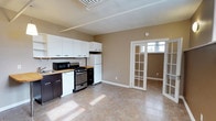Located at 117 North Essex Avenue in the charming borough of Narberth, PA, this single-floor space offers a functional and welcoming layout. The kitchen is well-appointed with white upper cabinetry, dark lower cabinets with a butcher block countertop, a stainless steel gas range, microwave, and a full-size refrigerator — providing ample storage and prep space. Stone-look tile flooring extends throughout, offering both durability and a clean, neutral aesthetic that ties the space together. Natural light filters in generously through a set of elegant French doors, which separate the kitchen and living areas while maintaining an open, airy feel. The warm, neutral wall tones complement the cabinetry and flooring, creating a cohesive and inviting atmosphere. Track lighting on the ceiling provides supplemental illumination. The overall layout is straightforward and efficient, making excellent use of the available footprint. Situated in Narberth, a walkable and vibrant community just outside Philadelphia, this space benefits from convenient access to local shops, dining, and transit options.