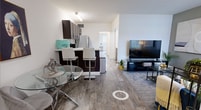 Located in Boca Raton, FL, this one-bedroom, one-bathroom apartment offers a well-designed layout that maximizes its compact footprint. The open-concept living and dining area is anchored by warm wood-style flooring that extends throughout the unit, creating a cohesive and inviting atmosphere. The living room features a neutral accent wall and large windows dressed with vertical blinds, allowing natural light to fill the space. A defined dining area comfortably accommodates a glass-top table, while the adjacent kitchen is outfitted with rich dark-espresso cabinetry, white countertops, a mosaic tile backsplash, stainless steel appliances, and a breakfast bar with seating — ideal for casual dining. A hallway connects the living areas to the private quarters of the unit. The generously sized bedroom features a wide mirrored sliding-door closet that enhances the sense of space, a large window with garden views, and enough room for both sleeping and a dedicated workspace. The bathroom includes a full tub-shower combination with tile surround, a vanity with dark cabinetry, and wood-style flooring that ties the space together. Two hallways provide functional transitions throughout the unit, completing this efficiently planned Boca Raton residence.