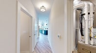 This thoughtfully designed two-bedroom, two-bathroom residence offers a well-appointed single-floor layout with a clean, contemporary aesthetic. Light wood-tone flooring runs through the main living areas, complemented by crisp white walls and an abundance of natural light from oversized windows and sliding glass doors.

The open-concept kitchen, dining, and living area serves as the heart of the home. The kitchen features striking teal-blue cabinetry contrasted by warm wood upper cabinets, a generous white quartz waterfall island with seating, stainless steel appliances, and stylish pendant lighting. The adjacent dining area is framed by floor-to-ceiling windows offering sweeping outdoor views, while the living room opens to a private deck through a large sliding glass door.

The spacious primary bedroom includes a dedicated walk-in closet with built-in shelving and hanging rods. The second bedroom is well-sized with its own closet access and a bright, neutral finish. Both bathrooms are finished in a modern style, with one featuring a sliding-glass enclosed shower, wood-toned vanity, and white quartz countertop.

Additional highlights include a dedicated laundry area with a stacked Whirlpool washer and dryer, light-filled hallways, and two closets providing ample storage throughout the home.