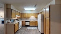 Located at 440 Cross Park Dr in Pearl, Mississippi, this single-floor residence offers a well-organized layout with functional living spaces throughout. The kitchen is a standout feature, designed in a generous U-shape with warm honey-toned oak cabinetry extending to the ceiling, granite-look countertops, and wood-look vinyl plank flooring. It is fully equipped with a range, dishwasher, and refrigerator, providing ample storage and counter space for everyday use. Adjacent to the kitchen, a dedicated dining area features rich hardwood-style flooring, a pendant light fixture, and an angled ceiling detail that adds architectural character. The bedrooms are carpeted and well-sized, each equipped with a ceiling fan and windows that allow natural light to filter in. The primary bathroom includes a single-sink vanity with a granite-look countertop, a built-in linen closet for extra storage, and a shower-tub combination. A secondary bathroom mirrors the same clean, functional design with hardwood-style flooring and a tub-shower combo. Neutral warm-beige tones and textured ceilings carry consistently throughout the residence, creating a cohesive and comfortable atmosphere suited for everyday living.