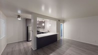 Located at 3851 N 28th St in Phoenix, Arizona, this single-floor unit offers a clean, modern aesthetic with a thoughtfully designed layout. The open-concept living and dining area features gray wood-look plank flooring and neutral white walls that create a bright, versatile space. A sliding glass door with vertical blinds allows natural light to filter in, adding to the airy feel of the main living area.

The kitchen is a standout feature, boasting a peninsula with a crisp white countertop and dark cabinetry that opens to the living space, creating a seamless flow ideal for entertaining. Pendant lighting accents the peninsula, while track lighting illuminates the work areas. Stainless steel appliances, including a full-size refrigerator, electric range, and microwave, are complemented by ample upper and lower dark cabinetry and a double-basin sink.

The bedroom is generously sized with the same wood-look flooring, neutral tones, and a window providing natural light. The bathroom is finished with neutral large-format tile surrounding a full soaking tub and shower combination, with coordinating tile flooring. The overall design throughout the unit reflects a contemporary and well-maintained interior, offering a comfortable living environment in the heart of Phoenix.