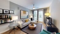 Located at 4700 Berwyn House Rd in College Park, Maryland, this thoughtfully designed single-floor residence offers a cohesive blend of modern style and functional living. The open-concept kitchen is a standout feature, showcasing dark cabinetry contrasted by crisp white quartz countertops, a subway tile backsplash, and a full suite of stainless steel appliances including a refrigerator, range, and microwave. A generously sized island with seating provides an ideal space for casual dining or entertaining. Track lighting and warm wood-look flooring complete the kitchen's contemporary aesthetic. The living area is bathed in natural light through floor-to-ceiling sliding glass doors that open to an outdoor view, complemented by a ceiling fan and durable hardwood-style flooring throughout. The bedrooms feature plush carpeting and large windows that invite natural light, with one bedroom dressed in rich teal accent walls for a bold, sophisticated feel. Closet space is thoughtfully incorporated near the bathrooms. The bathrooms include one full bath with a tub-shower combination and wood-look flooring, and an en-suite bath featuring a walk-in shower, vanity with white countertop, and coordinating teal accent walls. The overall ambiance throughout the residence is clean, contemporary, and welcoming.