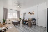 Located at 608 S Westlake Ave in Los Angeles, CA, this thoughtfully laid-out single-floor unit offers a clean, modern aesthetic throughout. The space is organized to maximize functionality, comprising a living room, kitchen, bathroom, hallway, entrance, and two closets.

The living room serves as the heart of the unit, featuring light hardwood-style flooring, tall ceilings, and a ceiling fan that enhances airflow and comfort. Large windows dressed with soft gray curtains allow generous natural light to fill the room, creating a bright and airy atmosphere. The crisp white walls amplify the sense of openness.

The kitchen is neatly appointed with two-tone cabinetry — white upper cabinets and sage-green lower cabinets — complemented by a clean white countertop, a single-basin sink, and stainless steel appliances including a full-size refrigerator. Decorative wall shelving adds a charming touch to the space.

The bathroom maintains the unit's clean, minimalist design with all-white fixtures, a vanity with mirror, and a window for natural ventilation. Two dedicated closets provide practical storage solutions throughout the unit.

The entrance and hallway offer a smooth transition into the living areas, maintaining the cohesive, light-filled character found throughout this well-designed Los Angeles residence.