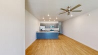 Located at 130 N Cedar St in Centerton, AR, this well-designed one-bedroom, one-bathroom unit offers a thoughtful, open-concept floor plan with consistent light wood flooring throughout. The combined kitchen and living area serves as the heart of the space, featuring a striking blue island with granite countertops that doubles as a prep and gathering area. The kitchen is fully equipped with stainless steel appliances, including a refrigerator with ice maker, a range, a built-in microwave, and a dishwasher, all complemented by sleek gray shaker-style cabinetry and recessed lighting above. The open living area benefits from natural light streaming through large windows with blinds, and a ceiling fan adds both style and comfort. A glass-panel exterior door provides additional light and outdoor access. The generously sized primary bedroom is bright and airy, with a ceiling fan, a window for natural light, and direct access to a spacious walk-in closet outfitted with multiple rods and shelving along all walls, offering ample storage. Clean white walls and neutral tones throughout the unit create a bright, modern ambiance that is both functional and inviting.