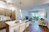 Located at 7631 W Atlantic Ave in Delray Beach, FL, this single-story, 2-bedroom, 2-bathroom residence offers a thoughtfully designed open-concept layout. Rich wood-style flooring flows throughout the living areas, anchoring the bright, neutral interiors. The kitchen is well-appointed with stainless steel appliances, warm wood cabinetry extending to the ceiling, white quartz countertops, and a breakfast bar with pendant lighting overhead — seamlessly connecting to the dining and living areas. The dining space accommodates a full dining table and is accented by clean white walls ideal for artwork. The living room is generously sized, featuring a ceiling fan and large sliding glass doors that open to a private balcony overlooking lush greenery. Both bedrooms feature wood-style flooring, ceiling fans, and windows with outdoor views. The spacious primary bedroom offers ample natural light. Each bathroom is finished with white cabinetry, quartz countertops, and tile flooring. Throughout, the residence maintains a bright, contemporary aesthetic suited to Florida living.