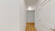 Located at 226 W Glebe Rd in Alexandria, Virginia, this modern residence offers four bedrooms and four bathrooms across a thoughtfully designed single-floor layout. Light hardwood flooring runs throughout, complementing the clean white walls and recessed lighting that give the space a bright, contemporary feel.

The open-concept kitchen is a standout feature, equipped with sleek two-tone cabinetry in white and charcoal gray, a large center island with a gas cooktop and crisp white quartz countertop, a stainless steel range hood, double wall ovens, and a full-size refrigerator. Large windows flood the kitchen and living area with natural light and offer views of surrounding greenery.

The bedrooms are generously proportioned, each featuring expansive windows — including floor-to-ceiling corner window configurations — that bring in abundant natural light and outdoor views. The spacious primary bedroom includes direct access to a private balcony overlooking the streetscape. 

The four bathrooms are finished with large-format neutral tiles, floating wood vanities with white countertops, wall-mounted toilets, and glass-enclosed showers and soaking tubs, reflecting a consistent modern aesthetic throughout. The overall ambiance is clean, minimalist, and light-filled, ideal for contemporary urban living.