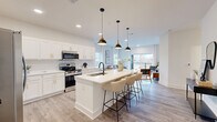 Located at 175 Black St in Rock Hill, SC, this well-appointed 2-bedroom, 2-bathroom residence offers a thoughtfully designed single-floor layout with a generous overall footprint. The open-concept living area seamlessly connects the kitchen, dining space, and living room, creating an inviting and functional hub for daily life. The kitchen is a standout feature, showcasing white shaker cabinetry with gold hardware, a white quartz waterfall island with bar seating, a subway tile backsplash, stainless steel appliances, and striking matte black and brass pendant lighting. Light wood-tone flooring flows throughout the main living areas, enhancing the bright, airy atmosphere. The living room opens to a private balcony through large sliding glass doors dressed with floor-to-ceiling drapes, allowing abundant natural light. The primary bedroom is a comfortable retreat with plush carpeting, and its en-suite bathroom features a double vanity with gold hardware, large-format marble-look tile, and a glass-enclosed walk-in shower. The second bathroom offers a full soaking tub with marble-style tile surround. Additional highlights include a dedicated office, in-unit laundry, a pantry, a utility room, and four closets—including a walk-in with wire shelving—providing excellent storage throughout.