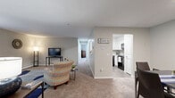 Located at 37 Sharon Rd in Waterbury, Connecticut, this 2-bedroom, 1-bathroom residence offers practical single-floor living within a well-organized floor plan. The exterior features classic brick construction, with a parking area surrounded by mature trees providing a natural backdrop.

The living room is generously proportioned, featuring soft carpeting, neutral gray walls, and a sliding glass door that fills the space with natural light and provides a view of the lush greenery outside. A charming pass-through window connects the living area to the kitchen, enhancing the open feel. The adjacent dining room, also carpeted, offers a comfortable area for meals and flows seamlessly into the kitchen, which is equipped with white cabinetry and modern appliances.

Both bedrooms are carpeted and finished in soft, neutral tones. The spacious primary bedroom features multiple windows that allow ample natural light and includes its own climate control unit. The second bedroom is equally comfortable, with large windows and generous floor space.

The bathroom is distinctively styled with warm yellow tile accents on the walls and surround, complemented by wood-look flooring, a white vanity, and a tub-shower combination. A dedicated closet provides additional storage within the unit. The overall ambiance is calm and functional, making this a comfortable and practical home.