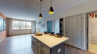 Located at 100 Oakview Dr in Trumbull, Connecticut, this single-floor residence offers a thoughtfully designed layout with modern finishes throughout. The heart of the home is a well-appointed kitchen featuring sage-green shaker-style cabinetry extending to the ceiling, stainless steel appliances including a gas range, microwave, dishwasher, and refrigerator, complemented by a white subway tile backsplash and crisp white countertops. A central kitchen island with pendant lighting overhead provides additional prep and dining space. Wood-look luxury vinyl plank flooring runs throughout the home, creating a cohesive and durable surface. The open living area is bright and airy, benefiting from large windows that invite generous natural light and offer outdoor views. A dedicated laundry closet with a stacked washer and dryer unit adds everyday convenience. The bedroom is a calm, well-proportioned space with a window providing natural light and room for comfortable furnishings. The full bathroom features tile flooring, a tub-shower combination with tile surround, a vanity with gray cabinetry, and a white countertop. Clean lines, neutral tones, and modern fixtures define the overall aesthetic of this functional and stylish residence.