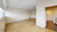 Located at 6320 Valley Way in Niagara Falls, Ontario, this two-bedroom, one-bathroom unit offers a well-organized single-floor layout with a clean, bright aesthetic throughout. Light wood laminate flooring runs through the main living areas and bedrooms, complementing the white walls and creating a warm, neutral atmosphere.

The galley-style kitchen is efficiently designed with white cabinetry, brushed nickel hardware, grey laminate countertops, tile flooring, and a window that draws in natural light. It is equipped with an electric range, microwave, and ample upper and lower cabinet storage. A hallway connects the kitchen to the rest of the unit, leading to a spacious living room that opens to a private balcony via sliding glass doors, offering views of the surrounding neighbourhood and greenery.

The primary bedroom is generously proportioned, featuring a large window, baseboard heating, and smooth white walls. The second bedroom is similarly bright, with its own window and baseboard heating unit. Both rooms offer a quiet, functional space.

The bathroom is finished with white subway tile surrounding a full bathtub and shower combination, dark floor tiles, and a small window for ventilation. The entrance and hallway provide a practical transition into the main living spaces, completing this well-laid-out unit.
