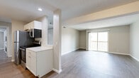 Located at 2431 SW Candletree Dr E in Topeka, Kansas, this single-floor home offers four bedrooms and three bathrooms within a thoughtfully laid-out floor plan. The galley-style kitchen is well-appointed with white shaker cabinetry, light quartz countertops, a grey subway tile backsplash, and stainless steel appliances including a refrigerator, range, microwave, and dishwasher. Light wood-look flooring runs throughout the kitchen and living areas, contributing to a clean, cohesive aesthetic. The combined kitchen and living area opens naturally toward a sliding glass door that leads to a private balcony, allowing natural light to fill the space. The living room offers a generous, open layout with neutral warm-toned walls and a textured ceiling. The bedrooms feature plush carpeting, windows for natural light, and closets with built-in shelving. Hallways connect the bedroom wing efficiently, finished with the same wood-look flooring. The bathrooms are clean and functional, featuring white vanities with integrated sinks, chrome fixtures, and mirror cabinetry. Throughout the home, a consistent neutral color palette and modern finishes create a bright, move-in-ready environment suited for comfortable everyday living.