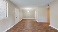 This single-floor residence offers a thoughtfully designed layout with a blend of hardwood-style flooring and plush carpeting throughout. The open living and dining area is bright and welcoming, featuring rich wood-tone flooring, neutral walls, a textured ceiling, and a pendant light fixture. French doors at the far end of the living space lead to an outdoor area, allowing natural light to fill the room.

The kitchen is well-equipped with white shaker-style cabinetry, granite-look countertops, a subway tile backsplash, and black and stainless steel appliances including a range, dishwasher, and refrigerator. A pass-through view connects the kitchen to the dining area, enhancing the open flow of the space.

The bedrooms are carpeted and finished with neutral tones, each featuring ceiling fans with light fixtures for added comfort. The primary bedroom includes a private en-suite bathroom and a dedicated closet. An additional bedroom offers a similarly comfortable layout. The bathrooms are finished with wood-style flooring, white vanities, and clean tub-shower combinations. Throughout the residence, white trim and baseboards provide a crisp, clean contrast to the warm neutral walls.