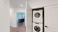 Located at 2140 Lakewood Rd in Toms River, NJ, this single-floor, 2-bedroom, 2-bathroom residence offers a clean, modern aesthetic throughout. Rich wood-look flooring runs continuously across the living spaces, complemented by crisp white walls and bright, natural light streaming through large windows in every room.

The kitchen is a standout feature, showcasing a two-tone design with white upper cabinets and dark lower cabinetry, white countertops, and a full suite of stainless steel appliances including a gas range, microwave, dishwasher, and French door refrigerator. A central island provides additional prep and dining space, while the adjacent dining area benefits from a stylish pendant light and a window overlooking the outdoors.

Both bedrooms are well-proportioned, bright, and inviting, with large windows that bring in generous natural light and views of surrounding greenery. The spacious primary bedroom offers comfortable living space. The two bathrooms are finished in a clean, contemporary style — one featuring a walk-in glass shower, extended vanity, and wood-look flooring, while the second offers a single vanity with ample storage. A dedicated hallway and closet complete the thoughtfully laid-out floor plan, making this a functional and attractive residence.