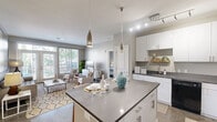 Located at 801 NW 10th St in Oklahoma City, this two-bedroom, two-bathroom residence offers a thoughtfully designed single-floor layout with contemporary finishes throughout. The open-concept kitchen is a standout feature, boasting crisp white cabinetry, dark countertops, black appliances, track lighting, and a central island with bar seating — ideal for both cooking and casual dining. Polished concrete floors run through the main living areas, adding an industrial-modern character to the space.

The living room is bright and inviting, anchored by French doors that open to a private balcony and allow generous natural light to fill the room. Both bedrooms are comfortably sized, with large windows offering outdoor views, neutral carpet flooring, and access to dedicated closets with built-in shelving. The primary bedroom connects to its own bathroom, which features a dark-topped vanity with white cabinetry and polished concrete floors.

The second bathroom is finished with large-format stone-look tile in the tub/shower surround, complementing the warm, neutral palette found throughout the residence. Each room reflects a clean, modern aesthetic, creating a cohesive and comfortable living environment well-suited for everyday life in Oklahoma City.