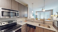 Located in the heart of Durham, NC, this single-floor residence at 605 W Chapel Hill St offers a thoughtfully designed living space with modern finishes throughout. Upon entry, rich hardwood-style flooring leads into an open-concept layout where the kitchen and living areas flow seamlessly together. The kitchen is a standout feature, boasting granite countertops, dark wood cabinetry, and a full suite of stainless steel appliances including an electric range, built-in microwave, refrigerator, and dishwasher. A peninsula with pendant lighting provides additional prep space and doubles as a casual dining area. The bedroom is a relaxing retreat, featuring plush carpeting, large windows dressed with stylish curtains that invite natural light, and a ceiling fan for year-round comfort. A dedicated walk-in closet with wire shelving and hanging rods offers generous storage. The bathroom is finished with tile flooring and includes a full tub and shower combination. Neutral tones and contemporary fixtures throughout create a cohesive, modern ambiance, making this residence a well-rounded and functional living space in downtown Durham.