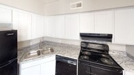Located at 2615 Pembroke Rd in Gastonia, NC, this single-story home offers a practical and well-appointed layout throughout. The kitchen is a functional highlight, featuring granite countertops with subtle gray and white veining, crisp white cabinetry extending to the ceiling, a double stainless steel sink, and black appliances including a range and dishwasher, all complemented by a ceiling-mounted ventilation system.

The main living area showcases durable wood-look vinyl plank flooring in a medium gray-brown tone, neutral gray walls, and a textured ceiling. Natural light enters through a window alongside a glass-paneled door, while a diagonal architectural detail on one wall adds visual interest. A hallway with matching LVP flooring and a wall-mounted light fixture connects the living areas to the bedrooms.

Multiple carpeted bedrooms offer neutral tones and individual windows fitted with blinds, allowing natural light throughout. Two bathrooms serve the home: one features a walk-in shower stall with built-in shelving and a grab bar, while the other includes a tiled tub-shower combination with a chrome fixture. The overall layout, as illustrated by the overhead floor plan view, provides a clear and efficient flow between all spaces.
