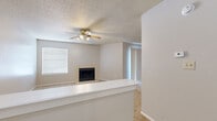 This single-story, one-bedroom, one-bathroom residence offers a well-organized layout across a comfortable footprint. The living room serves as the centerpiece of the space, featuring a tile-surround wood-burning fireplace, neutral-toned carpet, a ceiling fan with integrated lighting, and a textured ceiling. Natural light filters in through blinds-equipped windows, while a sliding glass door provides an additional source of light. A half-wall partition separates the living area from the kitchen, creating an open yet defined boundary between spaces.

The galley-style kitchen is efficiently arranged with warm wood cabinetry lining both sides, granite-look countertops, hardwood-style flooring, and white appliances including an electric range, microwave, and refrigerator. A double sink sits beneath upper cabinets on one side, maximizing storage and workspace.

The bedroom offers a comfortable area with carpet flooring, a ceiling fan, a window with blinds, and access to a generously sized closet fitted with multiple shelving rods. The bathroom includes a wood-cabinet vanity with a single sink, granite-look countertop, a large mirror, hardwood-style flooring, and a tiled tub surround.