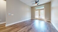Located at 201 N Church St in Mooresville, NC, this well-appointed 2-bedroom, 2-bathroom residence offers a thoughtfully designed single-floor layout. Rich hardwood-style flooring flows throughout the entire space, creating a cohesive and polished aesthetic.

The open-concept kitchen is a standout feature, showcasing white shaker cabinetry, granite countertops, a subway tile backsplash, stainless steel appliances, and a central island with pendant lighting and a undermount sink with a matte black faucet. Built-in open shelving adds functional character near the kitchen entry.

The living room is bright and welcoming, highlighted by a set of French doors topped with a transom window that invites abundant natural light and provides outdoor views. A ceiling fan completes the space.

The primary bedroom offers a comfortable footprint with large windows overlooking greenery, while the en-suite bathroom features a double-sink vanity with granite countertops, illuminated mirrors, matte black fixtures, and a glass-enclosed walk-in shower. A walk-in closet with wire shelving provides ample storage.

The second bedroom is bright with neutral tones, and the second bathroom includes a tub-shower combination, granite vanity, and matching matte black fixtures. Both closets are equipped with wire shelving systems throughout.