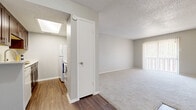 Located at 368 Irby Ln in Irving, Texas, this single-story unit presents a clean, neutral aesthetic throughout its thoughtfully arranged floor plan. The living area is generously proportioned, featuring plush wall-to-wall carpeting, soft gray walls, and a textured ceiling. A large sliding glass door fitted with vertical blinds allows natural light to fill the space while providing outdoor access. Consistent light-toned carpet extends into the bedrooms, each of which offers ample wall space and good natural light. One bedroom features a large window with horizontal blinds overlooking greenery outside, while another provides a comfortable, quiet retreat with a ceiling fan fixture.

The kitchen is positioned adjacent to the living area and is defined by a peninsula-style breakfast bar that creates a natural separation between spaces. Dark espresso cabinetry with light countertops contrasts well with the wood-look vinyl plank flooring found throughout the kitchen and entry areas. A skylight overhead brightens the kitchen naturally. In-unit laundry appliances are conveniently situated within the kitchen corridor. The bathroom includes a dark wood vanity with brushed nickel hardware, a tub-shower combination with a marble-style surround, and matching wood-look flooring, completing the cohesive design of the unit.
