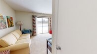 This one-bedroom, one-bathroom apartment at Woodbrook Apartments in Indianapolis, Indiana offers a thoughtfully organized layout across a single floor. The living area is bright and welcoming, featuring plush carpeting and a large sliding glass door that floods the space with natural light and provides direct access to an outdoor patio with exterior views. The living room flows seamlessly into a secondary seating area, offering flexible use of the space.

The dining room features warm hardwood-style flooring, a pendant light fixture overhead, and ample wall space, creating an inviting area for meals and entertaining. Adjacent to the dining room, the kitchen is equipped with oak cabinetry, granite-style countertops, and black appliances, including a range and dishwasher, all set over the same hardwood-style flooring.

The bathroom is finished with warm yellow walls, a wood vanity topped with a granite-style countertop, a large framed mirror, and hardwood-style flooring — offering a clean and functional design.

The bedroom provides a cozy retreat with soft carpeting, a window with outdoor views, and sufficient space for a full bedroom setup. Throughout the apartment, neutral wall tones create a cohesive, move-in-ready aesthetic well-suited for comfortable everyday living.