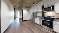 Located at 708 22nd Street in Greeley, Colorado, this two-bedroom, two-bathroom unit delivers a striking industrial-modern aesthetic across a well-proportioned single-floor layout. The design is defined by signature exposed concrete ceilings with visible ductwork and track lighting, bold dark door and window trim, and crisp white walls — a cohesive palette that lends the space a contemporary urban character.

The kitchen is a functional highlight, featuring stainless steel appliances including a refrigerator, range, microwave, and dishwasher, complemented by white shaker cabinets, dark stone-style countertops, and warm wood-tone hardwood flooring that extends through the main living areas.

Both bedrooms are carpeted for comfort, each with a window fitted with blinds and a wall-mounted PTAC unit for individualized climate control. The generously sized primary bedroom includes a dedicated closet. The industrial ceiling aesthetic carries throughout both rooms, maintaining design continuity.

The two bathrooms are clean and modern in finish. One features a full soaking tub with white subway tile surround, a floating vanity with a matte black faucet, and wood-tone flooring. The second is a compact, efficient full bath with a similarly minimalist aesthetic.

Two additional closets provide practical storage throughout the unit, rounding out this well-designed Greeley residence.