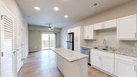 Located at 1735 E Valley Water Mill Rd in Springfield, MO, this one-bedroom, one-bathroom unit is thoughtfully designed to maximize functionality within a compact, single-floor layout. The open-concept kitchen and living area serves as the heart of the space, featuring warm wood-look flooring, recessed lighting, and a ceiling fan that enhances airflow throughout. The kitchen is well-appointed with crisp white shaker cabinetry, granite-style countertops, a center island with additional prep space, and a full suite of stainless steel appliances including a refrigerator, dishwasher, range, and microwave. A sliding glass door in the living area opens to a private balcony, bringing in natural light and outdoor views. The bedroom offers plush carpeting, a ceiling fan, and convenient access to both a walk-in closet and the adjacent bathroom. The bathroom continues the home's clean aesthetic with a white vanity and granite countertop. Additional practical spaces include a dedicated laundry area and utility room, rounding out this efficiently planned home with all the essentials for comfortable everyday living.