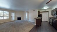 This single-floor residence offers a well-organized open-concept layout that seamlessly connects the living area and kitchen. The spacious living room is anchored by a classic white-framed fireplace and receives natural light through multiple windows. Neutral-toned carpet covers the living and bedroom areas, while dark hardwood-style flooring defines the kitchen and entryway, creating a clear visual distinction between the spaces.

The kitchen is thoughtfully designed with dark espresso cabinetry, granite-style countertops, and stainless steel appliances, including a range, microwave, and refrigerator. A peninsula with a built-in sink and breakfast bar extends into the living area, enhancing both functionality and flow. Ample upper and lower cabinet storage lines both sides of the galley-style kitchen corridor.

The bedrooms are generously proportioned, carpeted, and filled with natural light from sizable windows. At least one bedroom includes a walk-in closet with built-in shelving and hanging rods. The bathroom features a full soaking tub with white tile surround and an accent tile border, providing a clean and functional bathing space. Throughout the unit, neutral wall tones and consistent finishes create a cohesive, understated aesthetic.