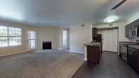 This single-floor residence offers a well-organized open-concept layout that seamlessly connects the living area and kitchen. The spacious living room is anchored by a classic white-framed fireplace and receives natural light through multiple windows. Neutral-toned carpet covers the living and bedroom areas, while dark hardwood-style flooring defines the kitchen and entryway, creating a clear visual distinction between the spaces.

The kitchen is thoughtfully designed with dark espresso cabinetry, granite-style countertops, and stainless steel appliances, including a range, microwave, and refrigerator. A peninsula with a built-in sink and breakfast bar extends into the living area, enhancing both functionality and flow. Ample upper and lower cabinet storage lines both sides of the galley-style kitchen corridor.

The bedrooms are generously proportioned, carpeted, and filled with natural light from sizable windows. At least one bedroom includes a walk-in closet with built-in shelving and hanging rods. The bathroom features a full soaking tub with white tile surround and an accent tile border, providing a clean and functional bathing space. Throughout the unit, neutral wall tones and consistent finishes create a cohesive, understated aesthetic.